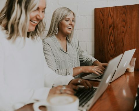 two women using laptops