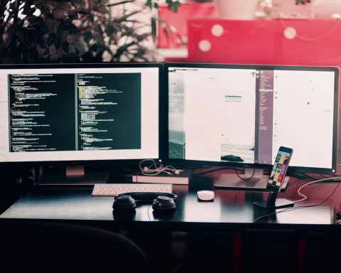 two black computer monitors on black table