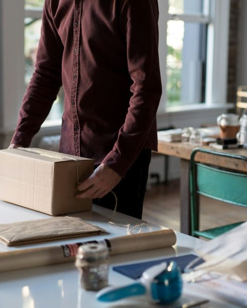 person holding cardboard box on table