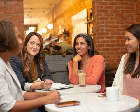four women chatting at cafe table