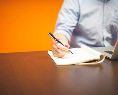 Vrouwelijke ondernemer die aantekeningen maakt aan haar bureau