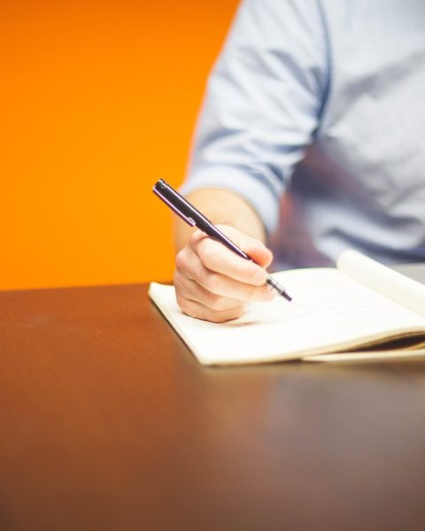 Vrouwelijke ondernemer die aantekeningen maakt aan haar bureau