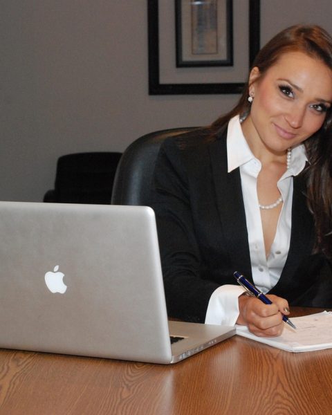 Vrouwelijke ondernemer schrijft productbeschrijvingen op haar laptop aan een bureau