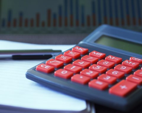 Vrouwelijke ondernemer berekent pensioeninleg aan bureau met laptop en notitieboek