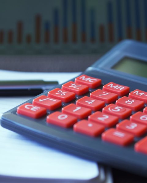 Vrouwelijke ondernemer berekent pensioeninleg aan bureau met laptop en notitieboek