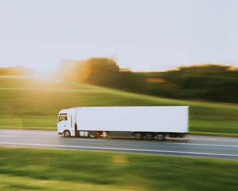 a white semi truck driving down a rural road