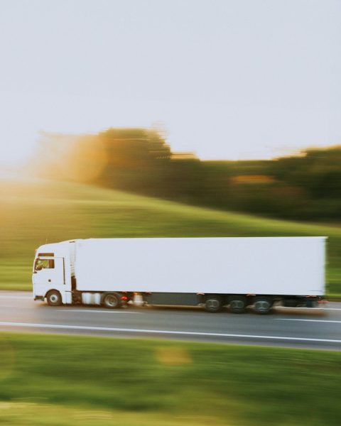 a white semi truck driving down a rural road