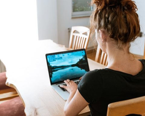Vrouwelijke ondernemer werkt aan laptop thuis aan haar digitale producten en administratie