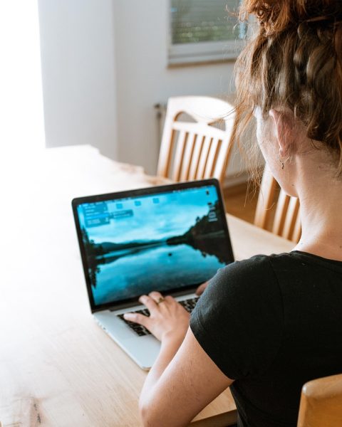 Vrouwelijke ondernemer werkt aan laptop thuis aan haar digitale producten en administratie