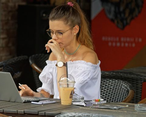 Een vrouw werkt 's avonds op haar laptop met een kop koffie naast zich