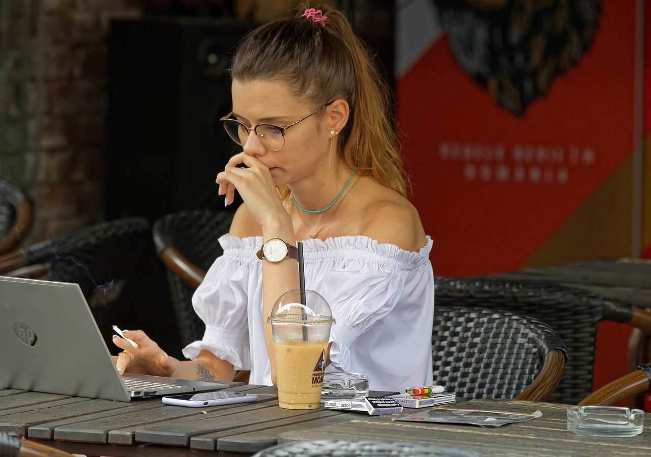 Een vrouw werkt 's avonds op haar laptop met een kop koffie naast zich