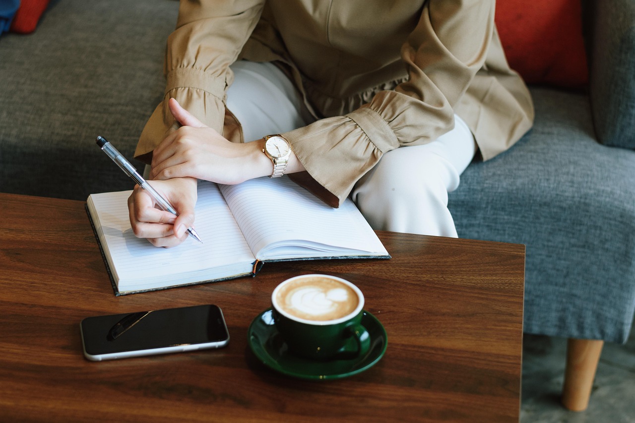 Vrouwelijke ondernemer aan bureau met notitieboek en laptop, nadenken over nieuwe strategie