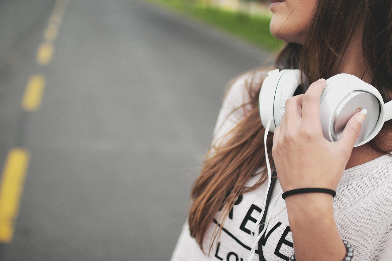 Vrouw luistert naar podcast met koptelefoon terwijl ze aantekeningen maakt in een notitieboek