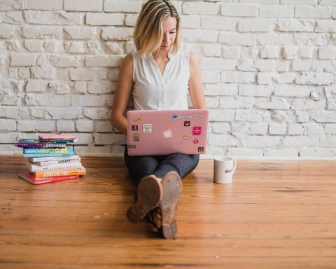 Vrouwelijke ondernemer zit achter haar laptop en denkt na over een zakelijk antwoord